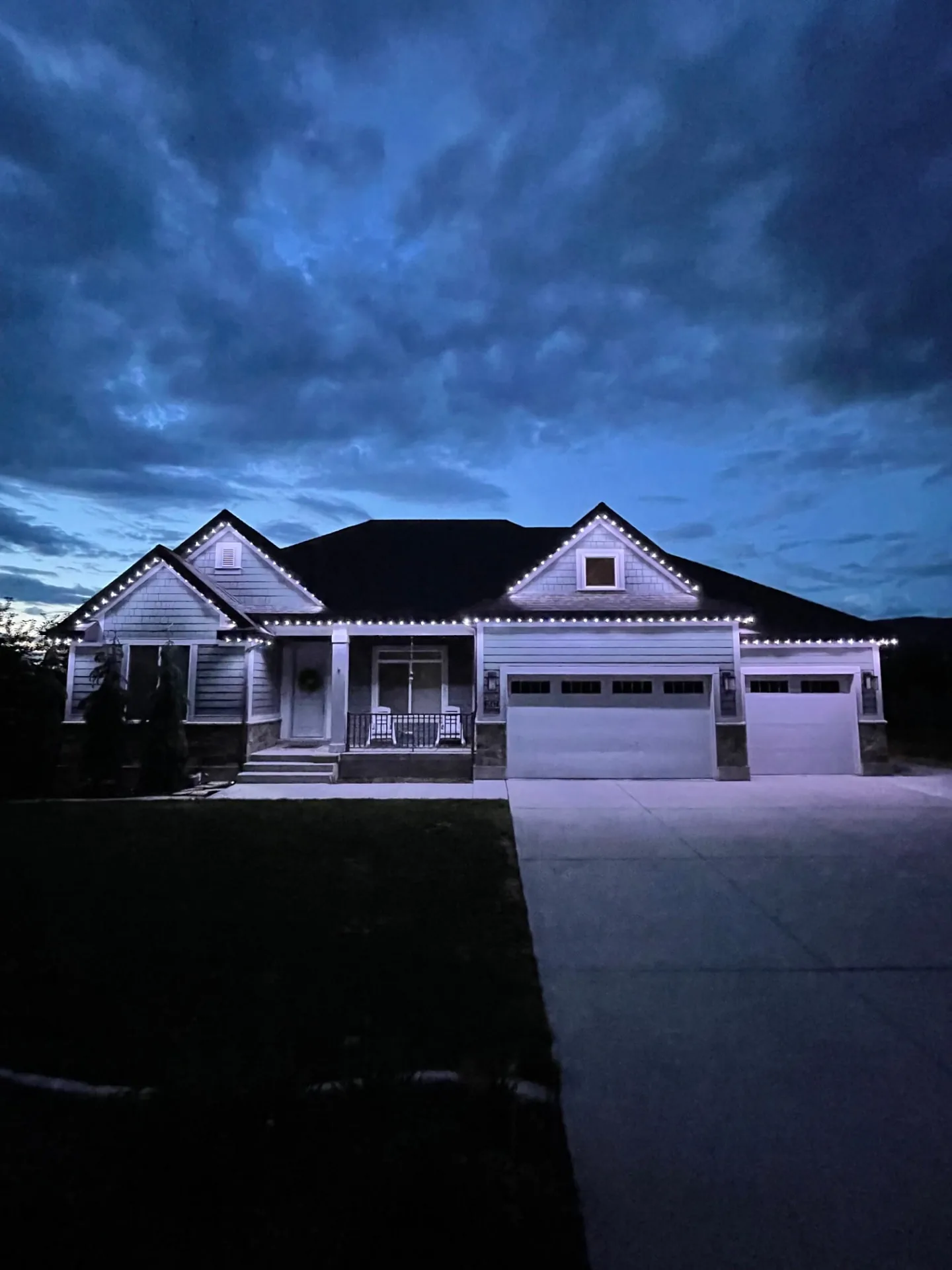 Home at dusk with bright white lights over the garage and porch